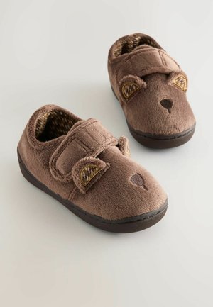 Braune Plüschhausschuhe mit Bärengesicht-Design, ausgestattet mit einem Klettverschluss und strukturierten Ohren. Aus weichem Material und mit dunkler Gummisohle.