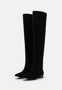 Botas negras de ante por encima de la rodilla, con puntera afilada y tacón bajo, que presentan una textura suave y mínimos acentos de costura.