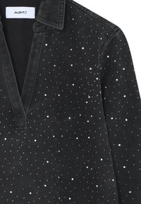 Pulover din denim negru cu decolteu în V și guler, având accente de paiete albe dispersate pentru textură și interes vizual.