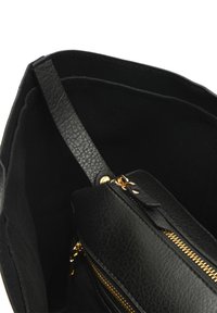 Čierna kabelka s textúrovaným koženým exteriérom, zlatým zipsom a priestranným čiernym interiérom s viacerými priehradkami.