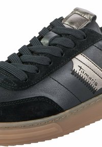 Sneaker nera con una combinazione di pelle liscia e texture di suede. Presenta dettagli metallici argentati, lacci piatti e una suola in gomma.