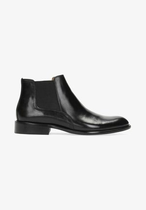 Bota Chelsea de cuero negro con paneles laterales elásticos, textura lisa, puntera redonda y tacón bajo apilado. Diseño minimalista sin adornos.