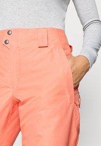 Κοραλί χιόνι παντελόνι με λεία υφή, ρυθμιζόμενη μέση και πλαϊνές τσέπες; διαθέτει μαύρα κουμπιά και ελαστικό κορδόνι.