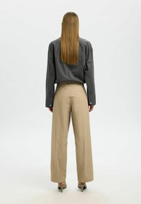 Gestreepte grijze shirt met lange mouwen, gecombineerd met beige wijde broek. De outfit heeft eenvoudige hardware en een ontspannen pasvorm.