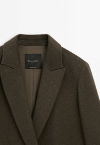 Blazer en laine marron foncé avec col à revers cranté et étiquette de la marque Massimo Dutti visible à l'intérieur du col.