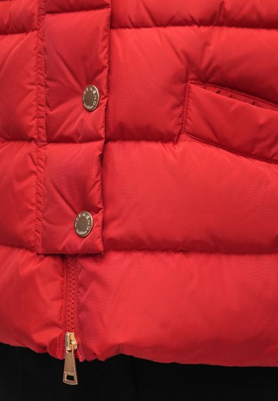 Nahaufnahme einer roten Steppjacke mit Metall-Druckknöpfen und der Aufschrift "Weekend MaxMara" sowie einem goldfarbenen Reißverschlussanhänger.