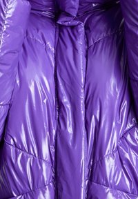 Fialová péřová bunda s lesklým, zrcadlícím se povrchem. Obsahuje prošívané panely, přední zapínání a design s vysokým límcem. Měkká textura.