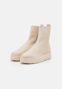 Beige leather ankle boots with a smooth texture, broad platform sole featuring a ridged design, and short zipper accent at the back.