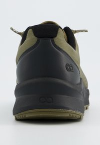 Chaussure de sport verte et noire avec une tige texturée, un col rembourré et une semelle en caoutchouc avec des motifs de traction. Logo sur le talon.