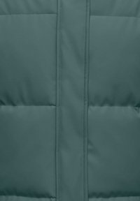 Vadderad jacka i djup teal med en slät textur, utrustad med en central dragkedja och två horisontella quiltade fickor.