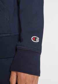 Navy Baumwoll sweatshirt mit einem gerippten Bündchen und einem kleinen gestickten Logo in Rot und Weiß. Strukturierter Stoff.