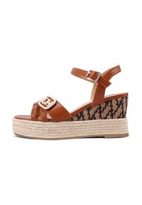 Sandali con zeppa in pelle marrone, caratterizzati da un motivo intrecciato, con una fibbia decorativa in oro e una piattaforma avvolta in juta. Design open-toe.