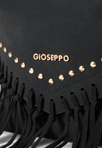 Černá taška z umělé kůže se zlatými nýty a třásněmi, s výrazným logem "GIOSEPPO" v horní části.