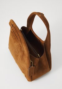 Borsa in suede marrone con doppio manico, apertura superiore e finiture in tonalità oro. Presenta una superficie testurizzata e un piccolo tag attaccato.