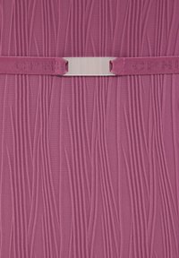 Rožinės spalvos audinys su vertikaliomis bangelėmis tekstūruotomis linijomis ir horizontalia rožine elastine juosta su skaidriu plastikiniu užsegimu centre.