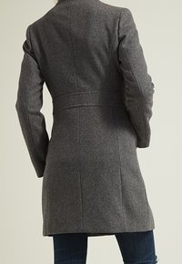 Grå ullkappa med skräddarsydd passform, med en strukturerad krage, långa ärmar och en smal midja, som sträcker sig till midtlårslängd.