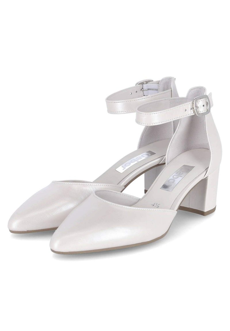 Białe skórzane buty na słupku z ostrym noskiem i paskiem wokół kostki. Gładka faktura z zapięciem na klamrę i odkrytymi bokami.