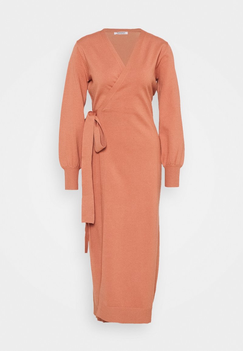 Lång, omslagsklänning i en mjuk terrakottafärg, med långa ärmar, ett band i midjan, och en mjuk stickad textur.