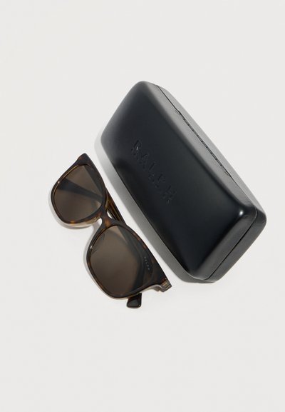 Γυαλιά ηλίου με τετράγωνο σκελετό σε σχέδιο χελώνας και σκουρόχρωμους φακούς δίπλα σε μαύρη σκληρή θήκη με ανάγλυφη λέξη "RALPH" πάνω σε λευκή επιφάνεια.