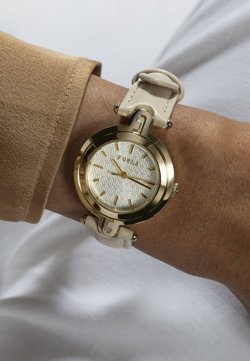 Orologio dorato con quadrante bianco texturizzato, cinturino in pelle beige e distintivi dettagli in metallo. Design classico con chiari markers delle ore.