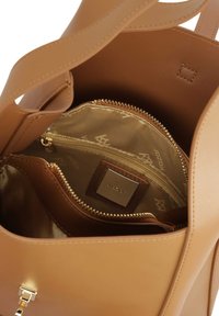 Beige handtas met een glad leren afwerking, voorzien van een ritssluiting aan de binnenkant, goudkleurige metalen details en een voering bedrukt met een logo.