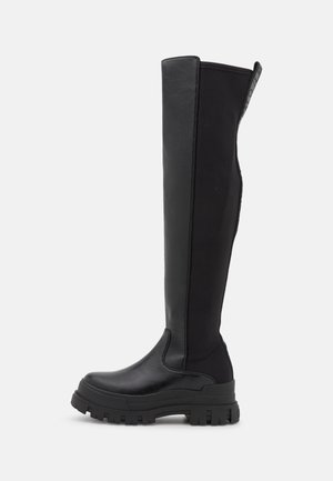 Botas de cuero negras hasta la rodilla con suela resistente, presentando un acabado liso y ligero acolchado en la parte trasera para mayor comodidad.