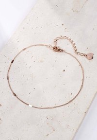Pulsera de cadena en oro rosa con segmentos texturizados y un pequeño charm en forma de corazón en el cierre. Acabado suave, diseño minimalista, longitud ajustable.