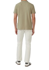 Korte mouwen, olijfgroene polo gemaakt van zachte stof, gecombineerd met witte, rechte jeans en casual zwart-wit sneakers.