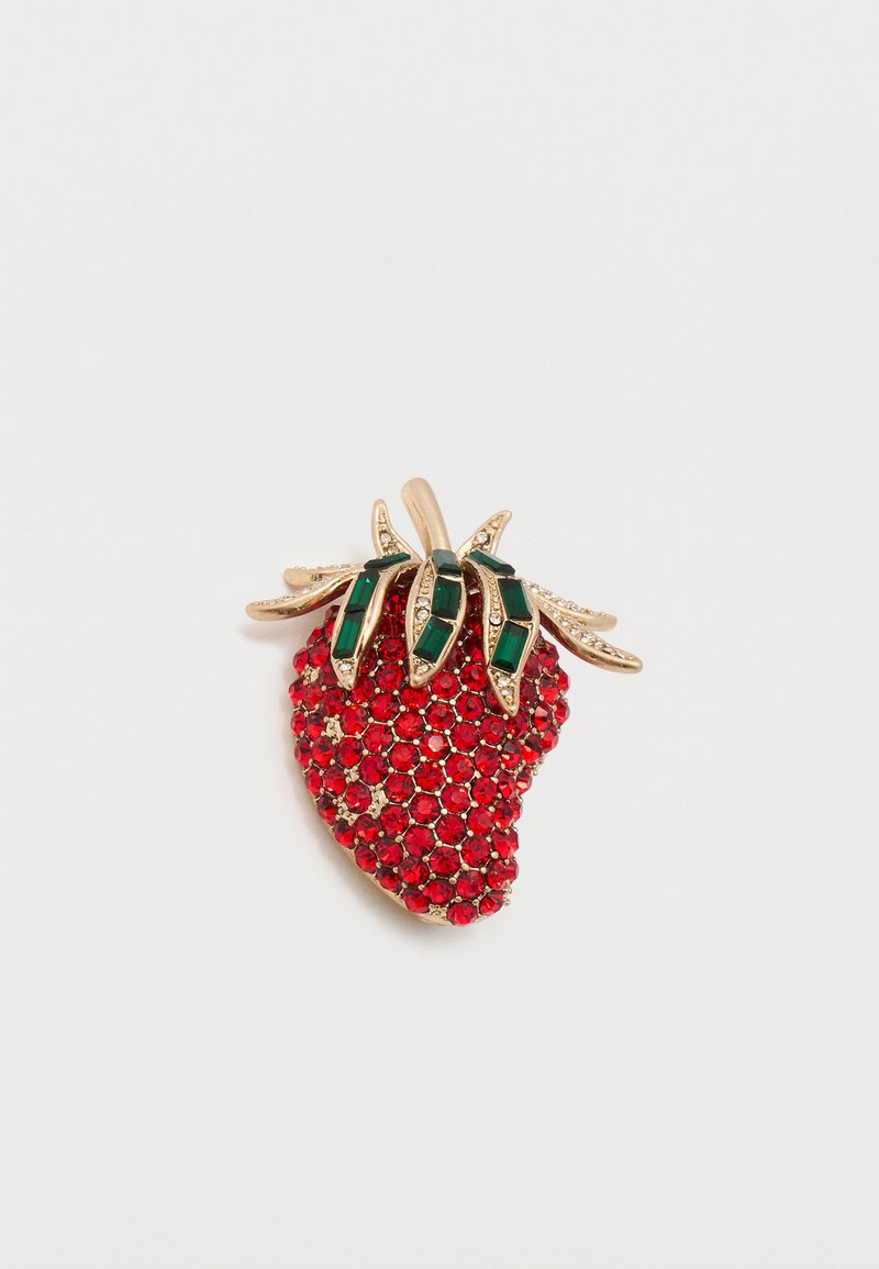 Broche fraise en cristal rouge avec des feuilles en métal doré ornées de cristaux rectangulaires verts et de petits cristaux clairs sur fond blanc.