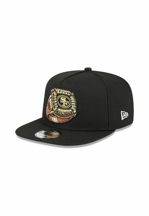 Black flat-brim cap with San Francisco 49ers Super Bowl Champions patch embroidered on the front and New Era logo on the side.