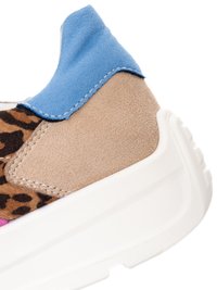 Tlustý bílý podpatek tenisky s béžovou semišovou částí, modrým poutkem a leopardím vzorem na tkanině.