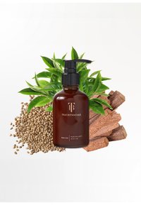 Amberfärgad glasflaska med en svart pump, märkt "True Botanicals Pure Radiance Body Oil", omgiven av gröna blad och träbitar.