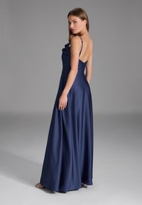 Robes de soirée en satin bleu marine avec un bodice ajusté, des détails en volants et une jupe fluide de longueur sol. Comprend des bretelles spaghetti fines et un dos décolleté.