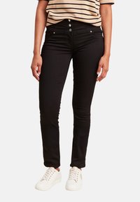 Jean skinny noir avec une taille haute et un design à cinq poches. Associé à un haut à rayures à manches courtes et des baskets blanches.