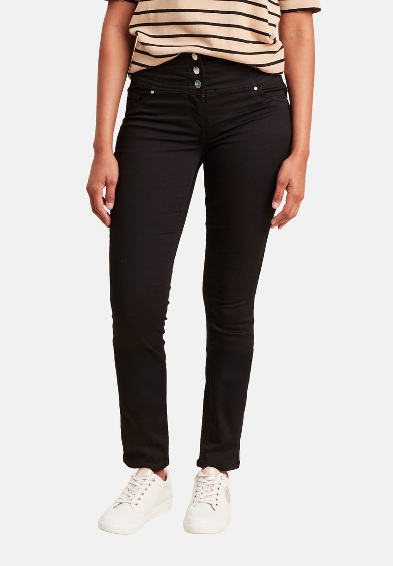 Jean skinny noir avec une taille haute et un design à cinq poches. Associé à un haut à rayures à manches courtes et des baskets blanches.
