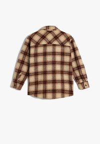 Camisa de cuadro con mangas largas, hecha de una tela texturizada. Los colores incluyen beige, marrón y azul marino. Presenta puños abotonados y un dobladillo curvado.