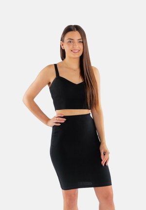 Czarny prążkowany top crop z cienkimi ramiączkami, zestawiony z czarną dopasowaną spódnicą, obie wykonane z teksturowanego materiału. Prosty design bez wzorów.
