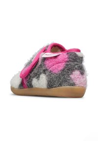 Pantofole in feltro grigio e bianco con motivi a cuore rosa, una fascia rosa sulla parte superiore e una suola flessibile in gomma marrone.