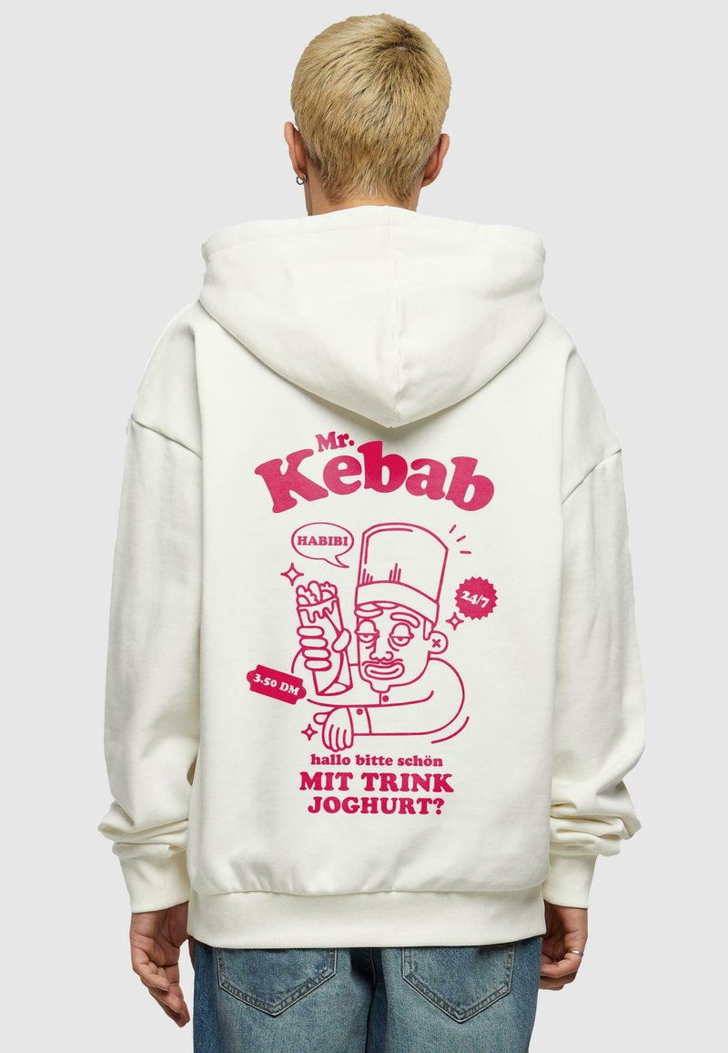 Kremfarget hettegenser med et stort rosa grafikk på baksiden, som viser en karakter som holder en kebab, med tekst og dekorative elementer.