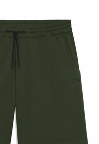 Mörkgröna shorts i luftigt material med perforeringar, elastisk midja, justerbar dragsko, sidoficka och svart logotypdetalj.