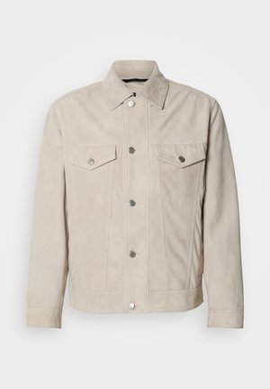 Casaco bege em camurça com fecho de botões à frente, dois bolsos no peito e uma gola clássica. Apresenta botões prateados e textura suave.