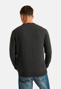 Pull en tricot gris foncé avec des manches longues et un col rond, présenté de dos, accompagné d'un jean en denim clair.