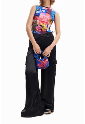 Färgglad ärmlös topp med blandade grafiska tryck med blommotiv; matchad med svarta breda satinbyxor och blå mönstrad handväska.