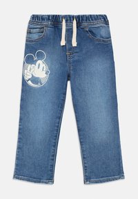 Jeans bleus pour enfants avec taille élastique et cordon blanc, ornés d'un imprimé de personnage de dessin animé faisant un signe de paix sur la jambe gauche.