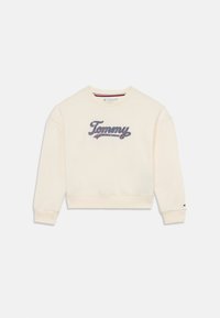 Sweatshirt crème avec des poignets et un ourlet côtelés, présentant un logo "Tommy" brodé en bleu et rouge à l'avant. Texture de tissu douce.