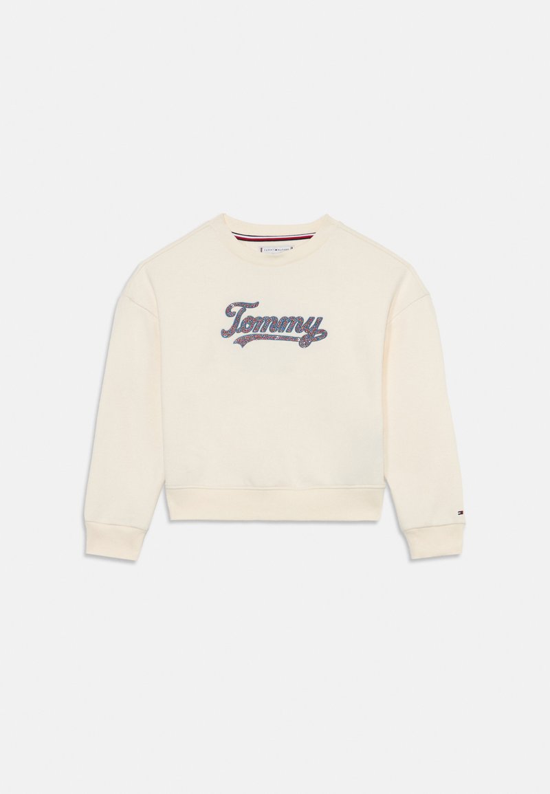 Sweatshirt crème avec des poignets et un ourlet côtelés, présentant un logo "Tommy" brodé en bleu et rouge à l'avant. Texture de tissu douce.