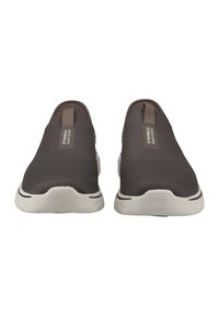 Dark gray slip-on shoes made of textured fabric with white rubber soles. Features a prominent logo on the heel and side for branding.