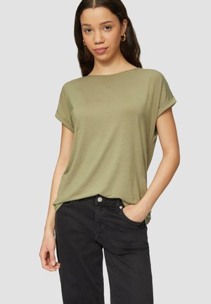 Haut vert olive à manches courtes avec une coupe ample et décontractée. Tissu doux, encolure ronde et manches retroussées, associé à un pantalon foncé.