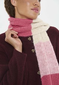 Strikket tørklæde med et gradientdesign i pink og cremefarver, bundet omkring halsen, lavet af blødt uldmateriale med en tekstureret finish.