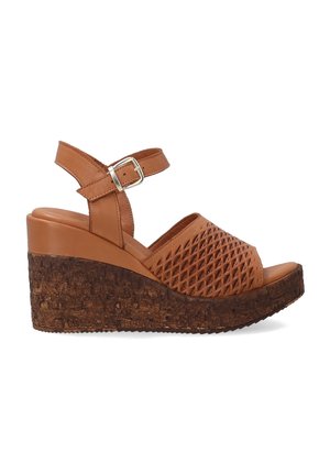 Brown wedge sandals with a textured cork sole, perforated upper design, and adjustable ankle strap featuring a metal buckle.